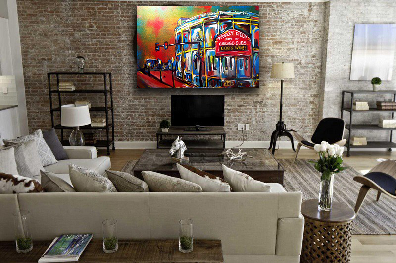 Painting of the Wrigley Field marquee under a red and yellow sky, hung above a television in a brick loft